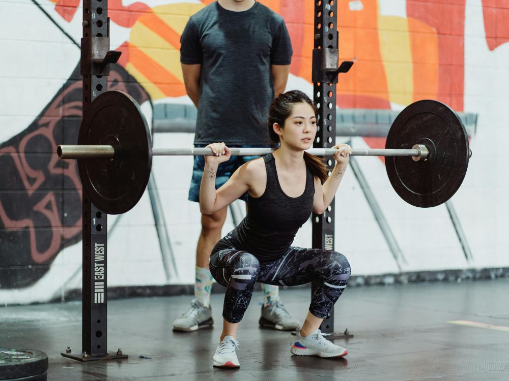 Mulher realizando agachamento, um dos exercícios que mais prezam pela postura correta.